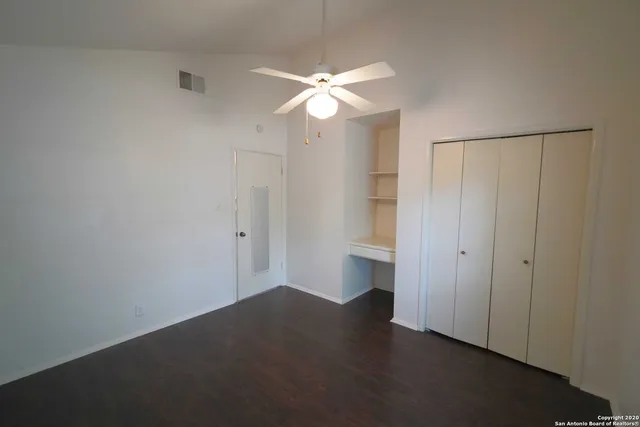 a view of a room with wooden floor and a ceiling fan