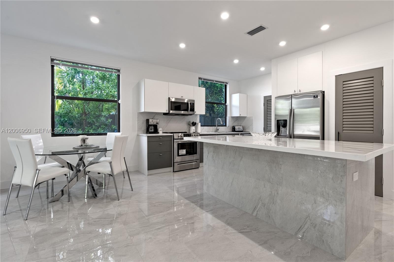 2889 Southwest 33rd Avenue, Unit 2889 Miami, FL 33133 - Photo 2 of 38 a kitchen with stainless steel appliances granite countertop a stove top oven a sink a dining table and chairs
