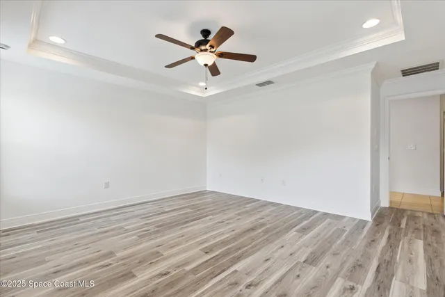 an empty room with wooden floor fan and windows