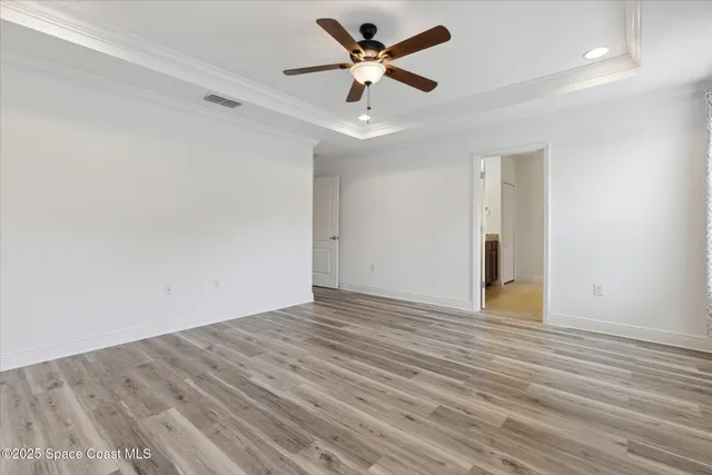an empty room with wooden floor and ceiling fan