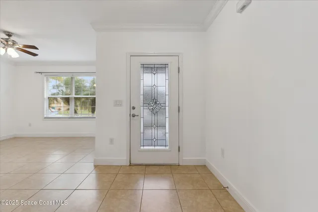 a view of an empty room with windows and chandelier fan