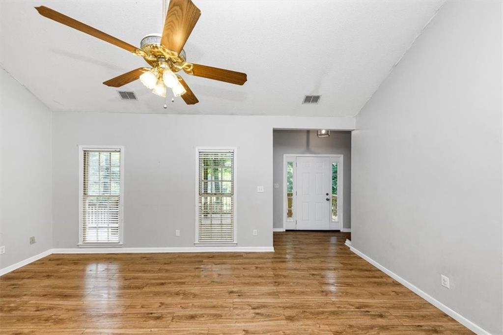 244 Freestone Lane Dallas, GA 30132 - Photo 4 of 26 an empty room with wooden floor chandelier fan and windows