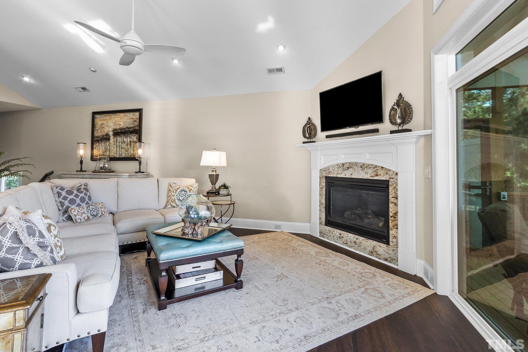 8737 Castleberry Road Apex, NC 27523 - Photo 82 of 99 a living room with furniture a fireplace and a flat screen tv