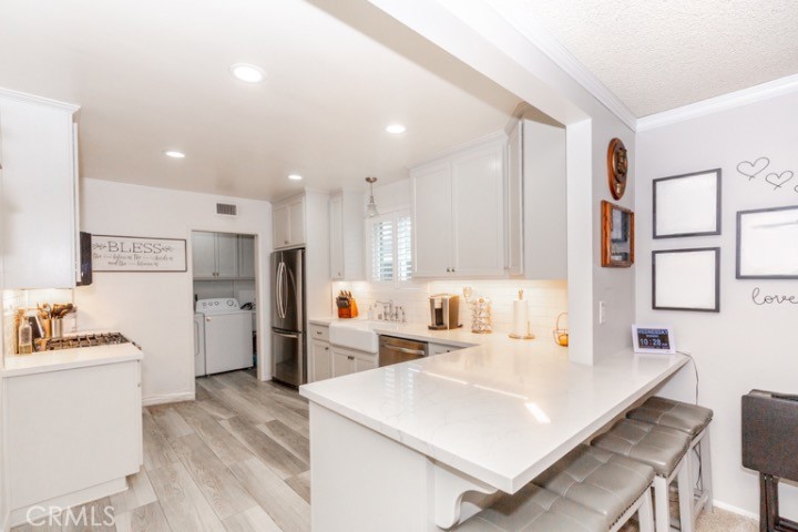 11229 Elmhurst Drive Norwalk, CA 90650 - Photo 16 of 54 a large white kitchen with kitchen island a stove a sink a refrigerator and white cabinets with wooden floor