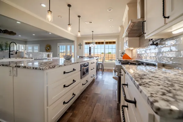 a kitchen with granite countertop a stove a sink a refrigerator and wooden floor