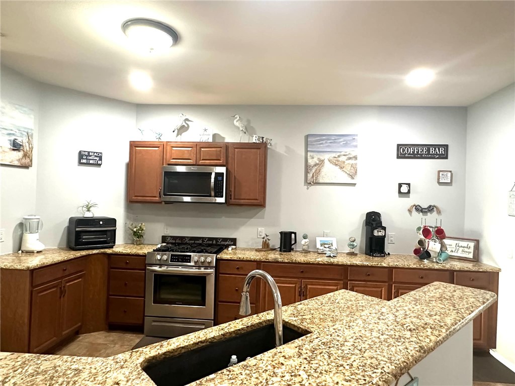 15517 Dyna Street Corpus Christi, TX 78418 - Photo 9 of 16 a kitchen with stainless steel appliances kitchen island granite countertop a sink and wooden cabinets