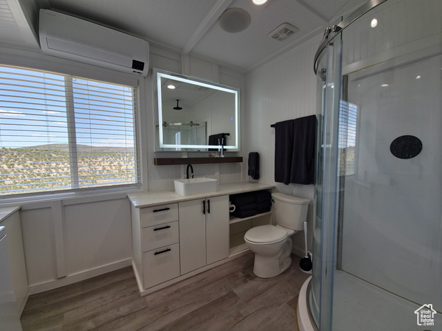 900 Altamont Road Evanston, WY 82930 - Photo 13 of 27 Bathroom with an AC wall unit, wood finished floors, vanity, a stall shower, and a decorative wall