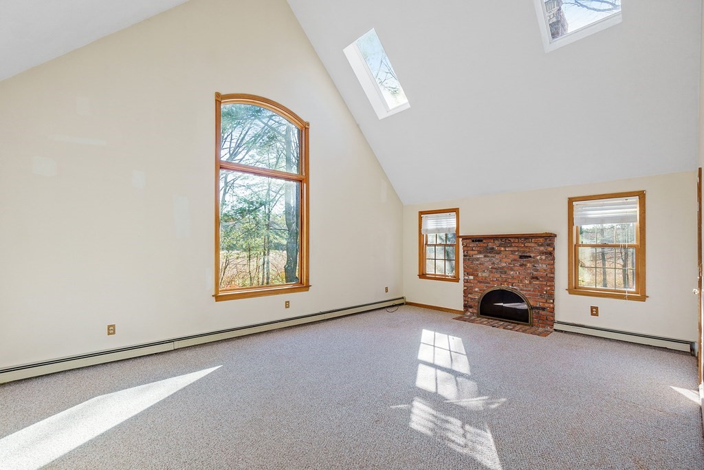 462 Lowell Road Groton, MA 01450 - Photo 16 of 42 a view of an empty room with a fireplace and a window