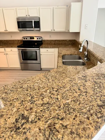 a kitchen with granite countertop white cabinets and sink