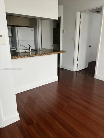 an empty room with wooden floor and mirror
