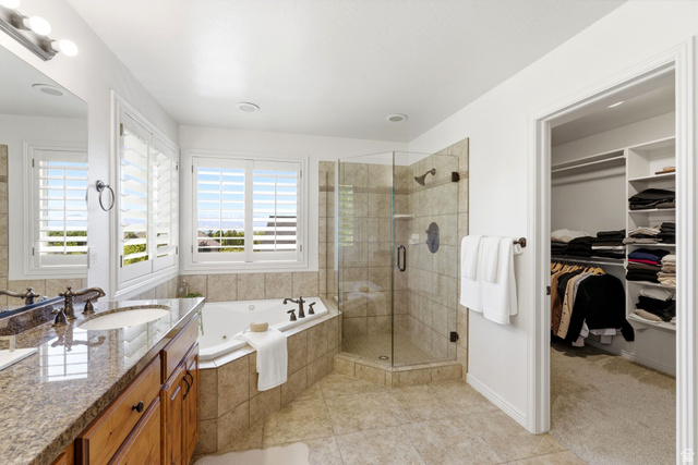 1712 Somerset Ridge Drive Draper, UT 84020 - Photo 35 of 76 Bathroom featuring a corner soaking tub, a separate glass-enclosed shower with tile surround, a double vanity with granite countertop and wood cabinetry, and a walk-in closet with built-in shelving