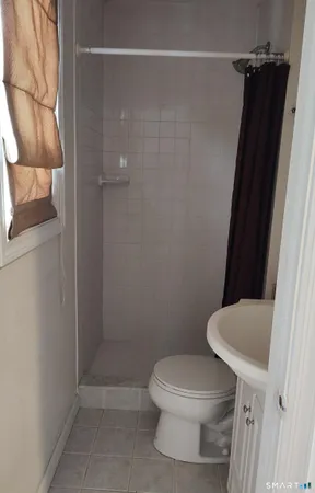 a white toilet sitting next to a shower