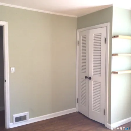 a view of a room that has wooden floor and a window