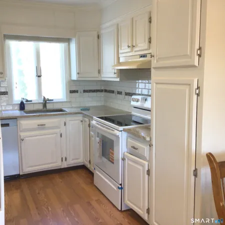 a kitchen with granite countertop white cabinets and white appliances