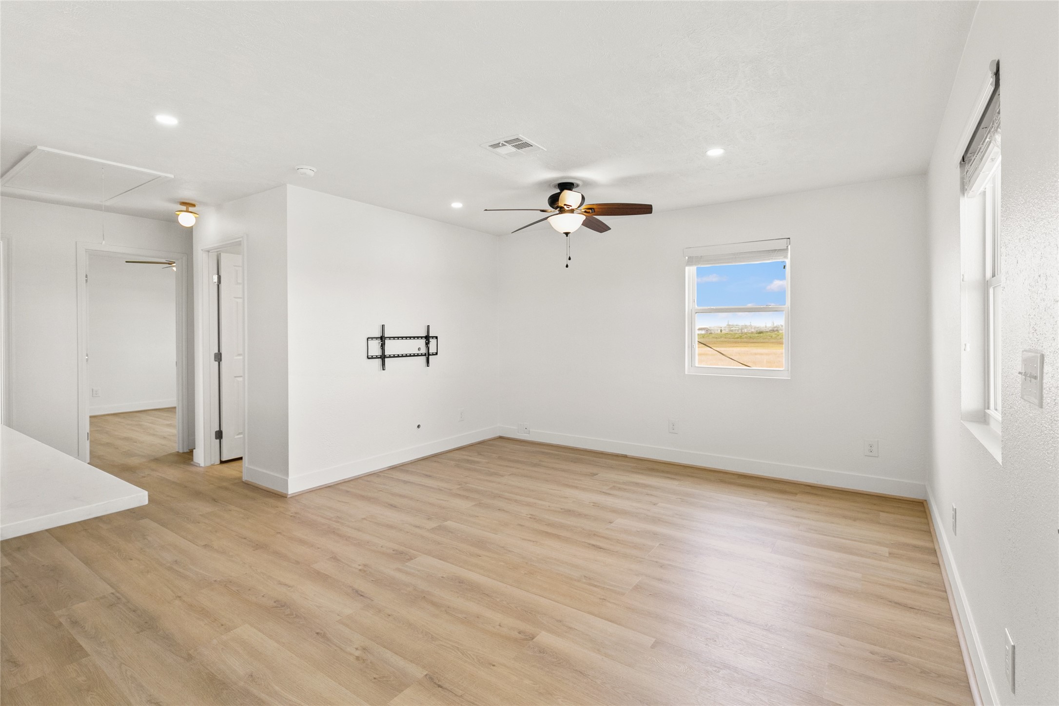 715 Caisson Street Surfside Beach, TX 77541 - Photo 17 of 35 an empty room with wooden floor chandelier fan and windows