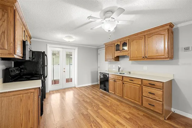 a kitchen with stainless steel appliances granite countertop a refrigerator a stove top oven a sink dishwasher and white cabinets with wooden floor