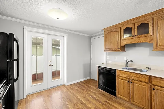 a kitchen with stainless steel appliances granite countertop a refrigerator a stove top oven a sink and dishwasher with wooden floor