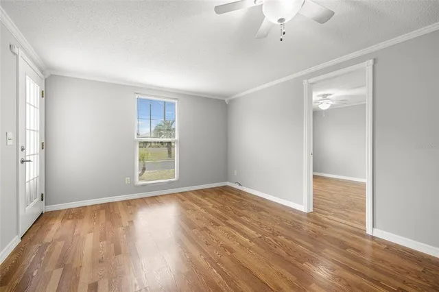 an empty room with wooden floor and windows