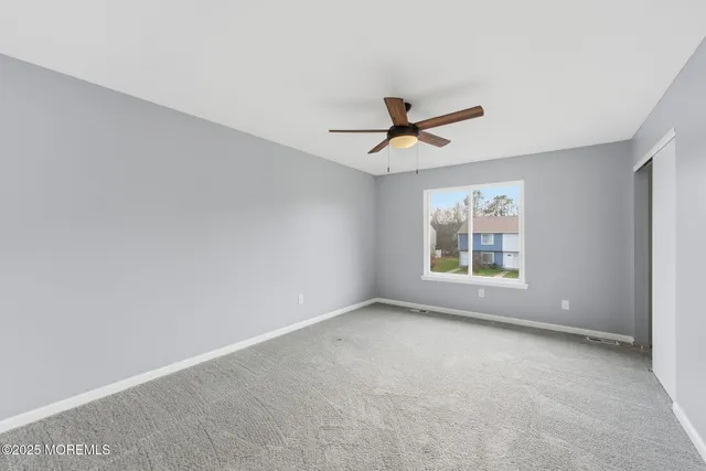 an empty room with window and ceiling fan