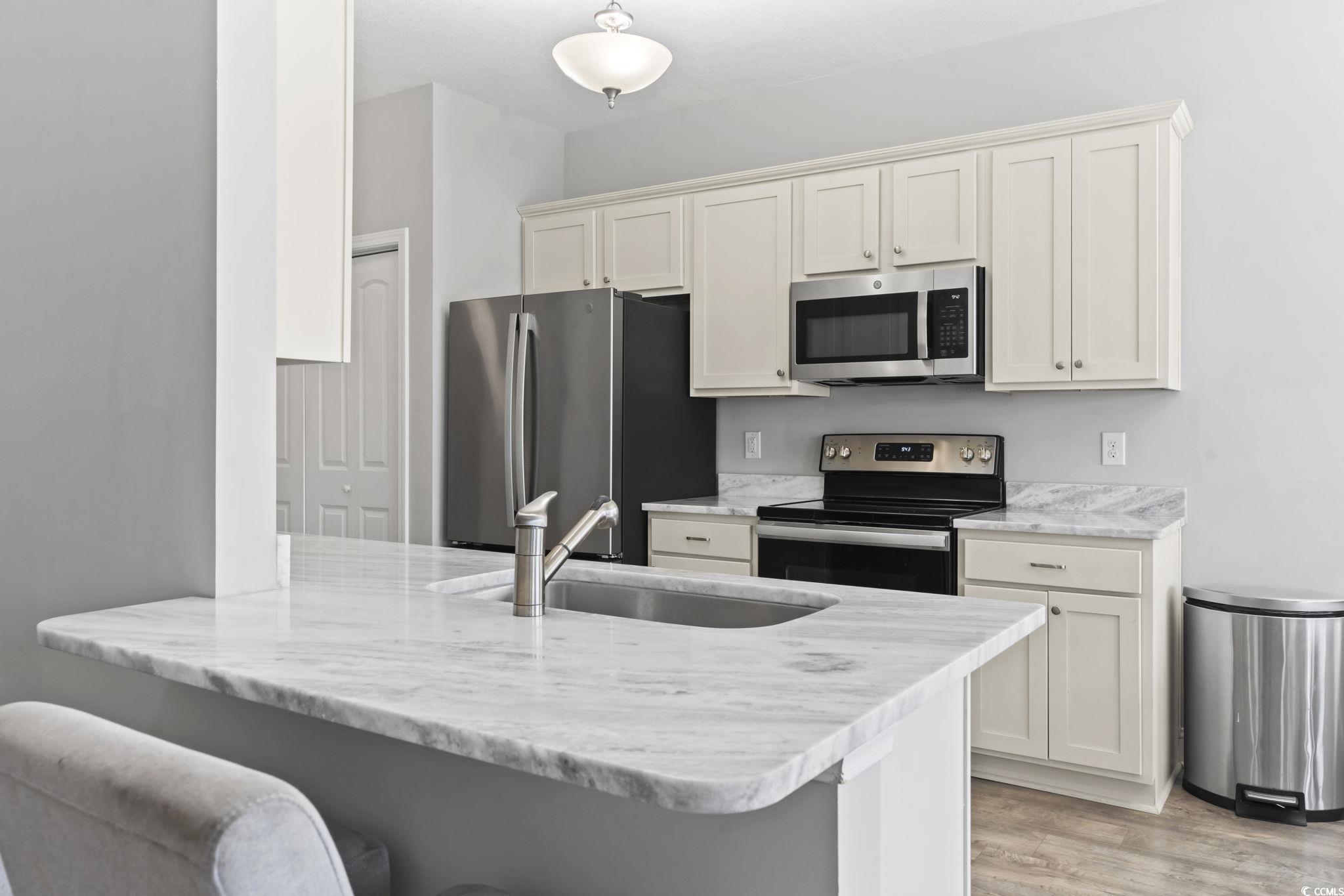 712 Hobonny Loop Longs, SC 29568 - Photo 13 of 39 Kitchen with a breakfast bar area, appliances with stainless steel finishes, a sink, a peninsula, and light wood-style flooring