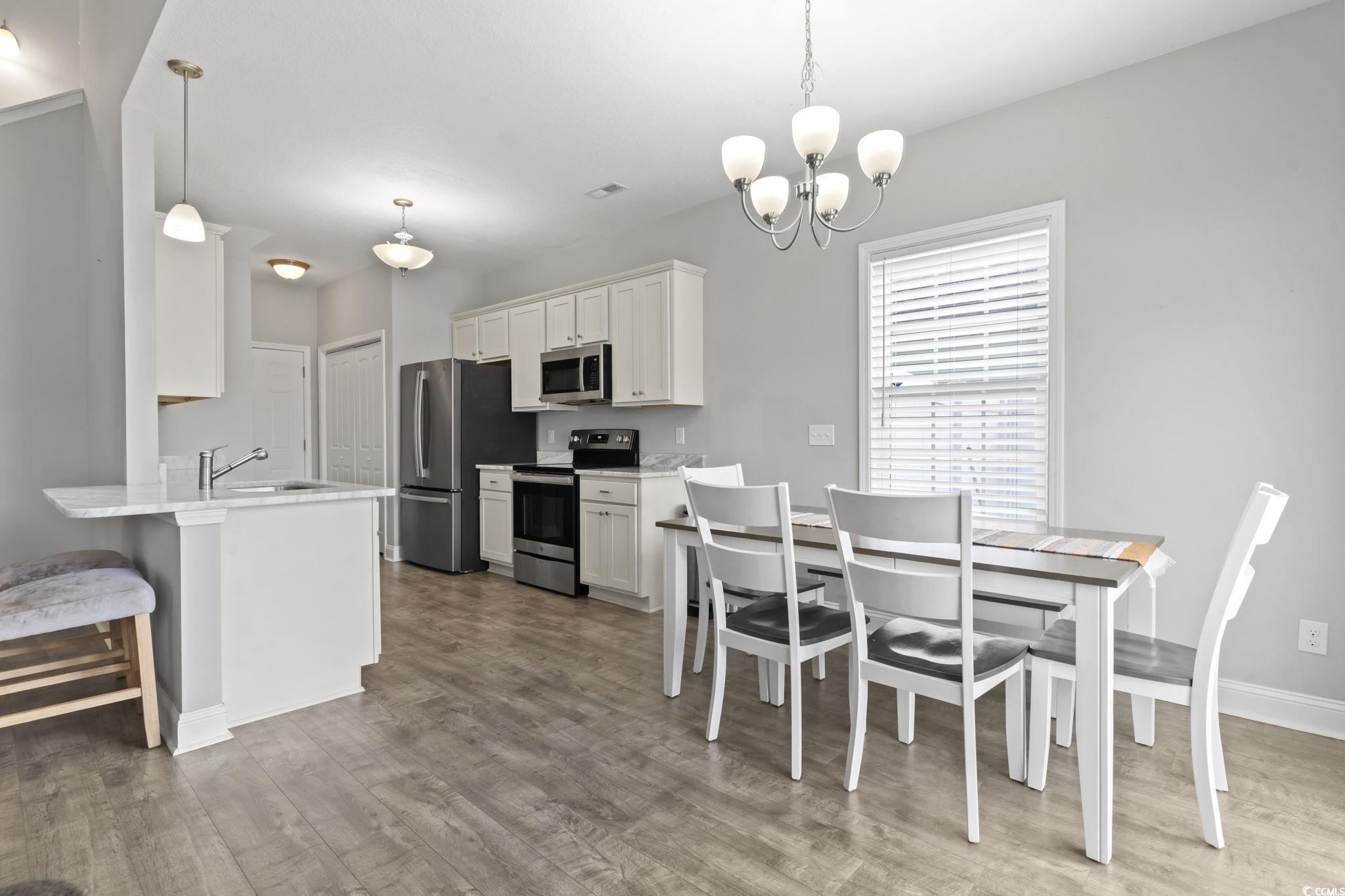 712 Hobonny Loop Longs, SC 29568 - Photo 18 of 39 Dining area with baseboards, wood finished floors, and a notable chandelier