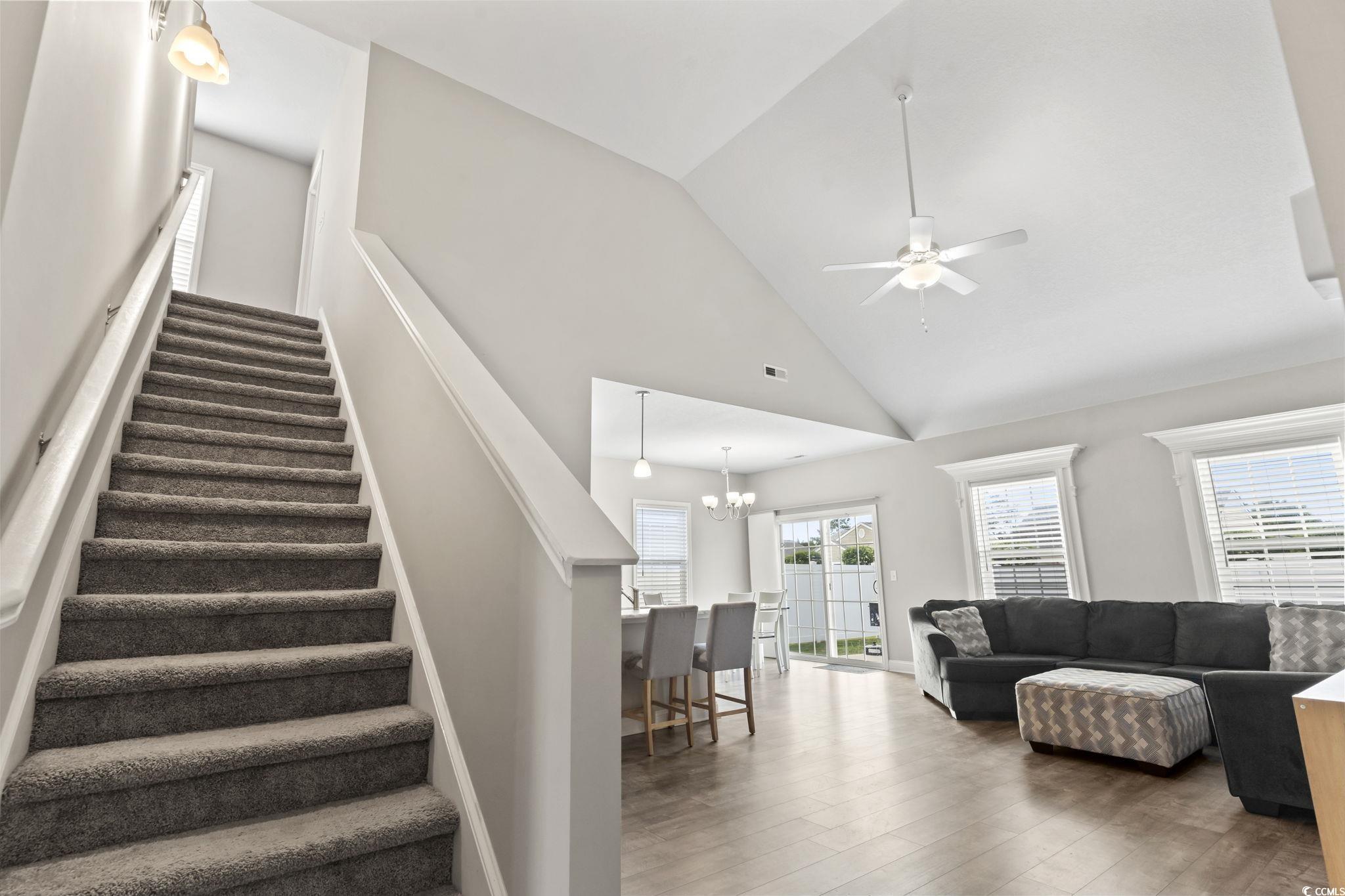 712 Hobonny Loop Longs, SC 29568 - Photo 9 of 39 Living area with visible vents, stairs, wood finished floors, high vaulted ceiling, and ceiling fan with notable chandelier