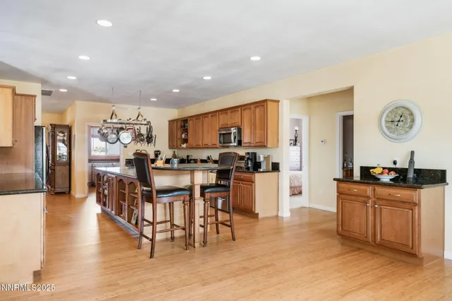 a kitchen with stainless steel appliances kitchen island granite countertop a dining table chairs and granite counter tops