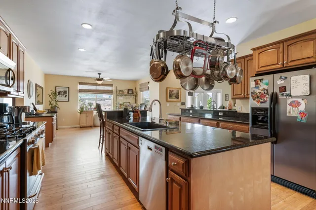 a kitchen with stainless steel appliances granite countertop a stove a sink dishwasher and cabinets with wooden floor
