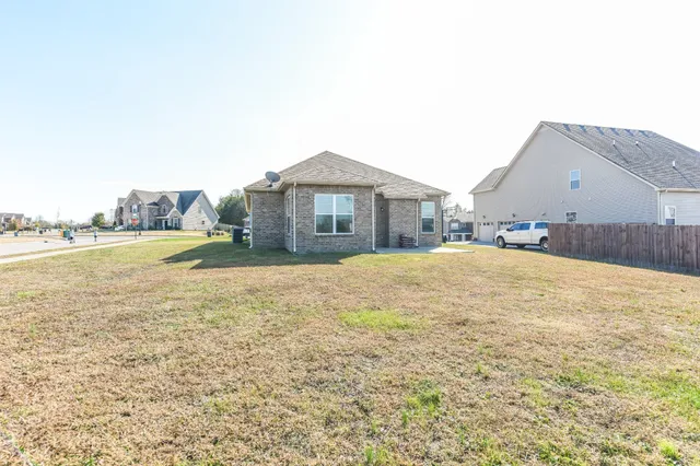 a view of a house with a yard and a large tree
