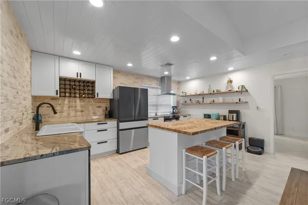a kitchen with stainless steel appliances kitchen island granite countertop a sink and a refrigerator