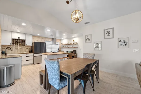 a dining room with stainless steel appliances kitchen island granite countertop a dining table chairs and a refrigerator