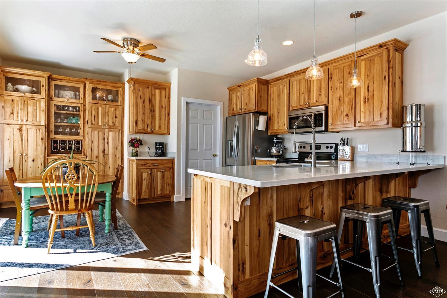 a kitchen with stainless steel appliances granite countertop a stove top oven a refrigerator a sink and a dining table with wooden floor