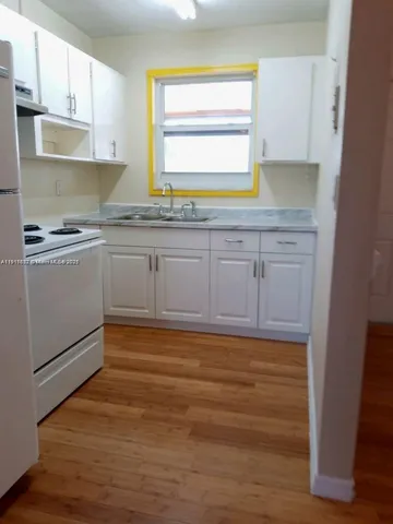 a kitchen with granite countertop white cabinets and white appliances