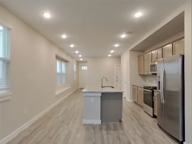 a kitchen with stainless steel appliances granite countertop a refrigerator a sink dishwasher a stove and white countertops with wooden floor