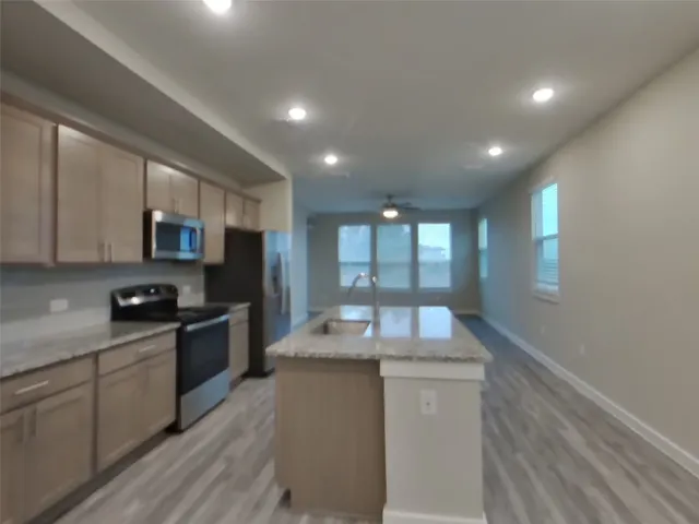 a kitchen with granite countertop kitchen island wooden cabinets and stainless steel appliances