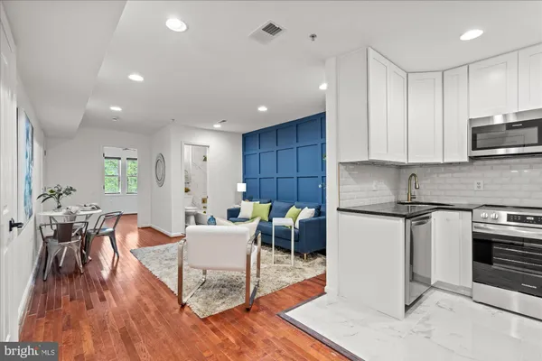 a kitchen with stainless steel appliances granite countertop a stove a sink a refrigerator and a granite counter tops with wooden floors