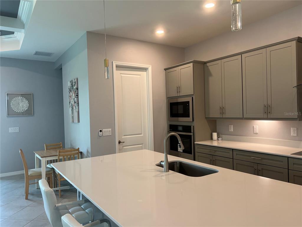 17535 Jadestone Court Venice, FL 34293 - Photo 11 of 92 a kitchen with kitchen island a stove a sink and a refrigerator with white cabinets