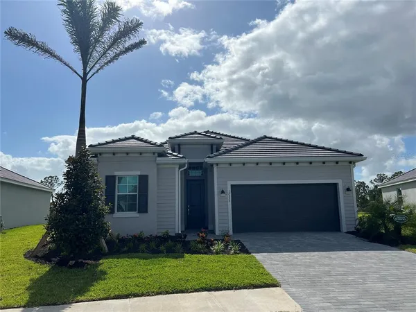 a front view of a house with a garden and trees