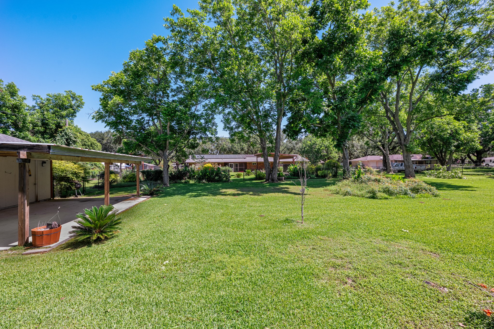 616 Cannan Drive Angleton, TX 77515 - Photo 34 of 49 Expansive backyard showcases a wide-open lawn framed by mature shade trees and established landscaping, creating a peaceful park-like atmosphere. With ample space for recreation, gardening, and outdoor gatherings, this private outdoor retreat offers exceptional room to enjoy the outdoors.
