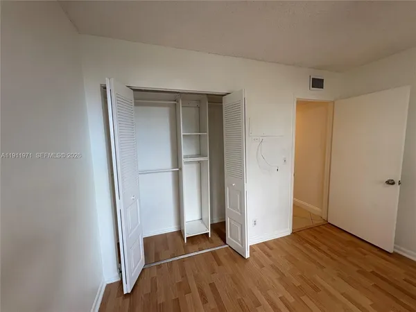an empty room with wooden floor and closet