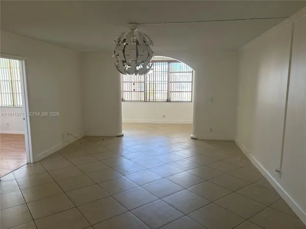 an empty room with kitchen view and natural light