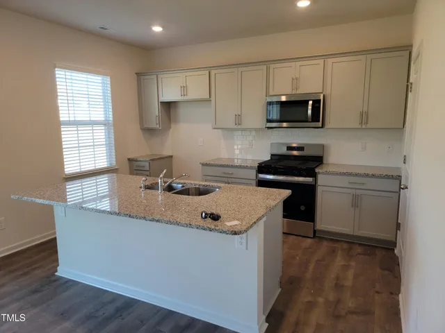 a kitchen with stainless steel appliances granite countertop a sink dishwasher a stove and a microwave oven with cabinets