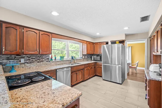 a kitchen with stainless steel appliances granite countertop a refrigerator and a stove top oven