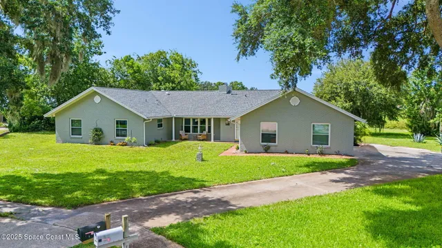 a view of a house with a yard and large trees