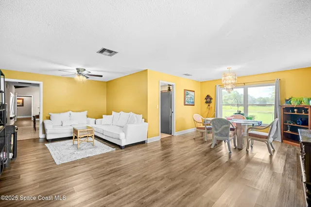 a dining room with furniture a chandelier and wooden floor