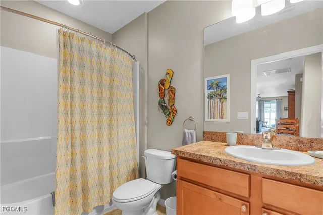 a bathroom with a granite countertop sink a toilet and shower curtain