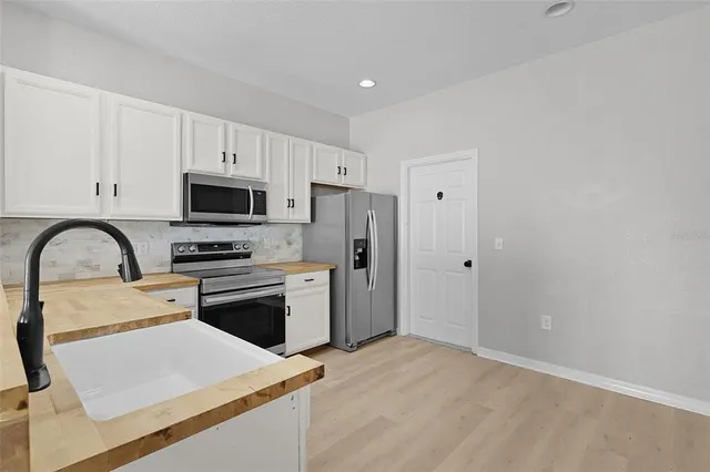 a kitchen with stainless steel appliances a refrigerator sink and white cabinets