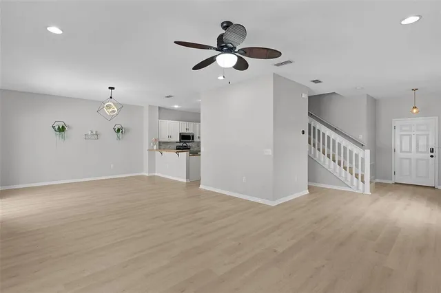 a view of empty room with wooden floor and ceiling fan