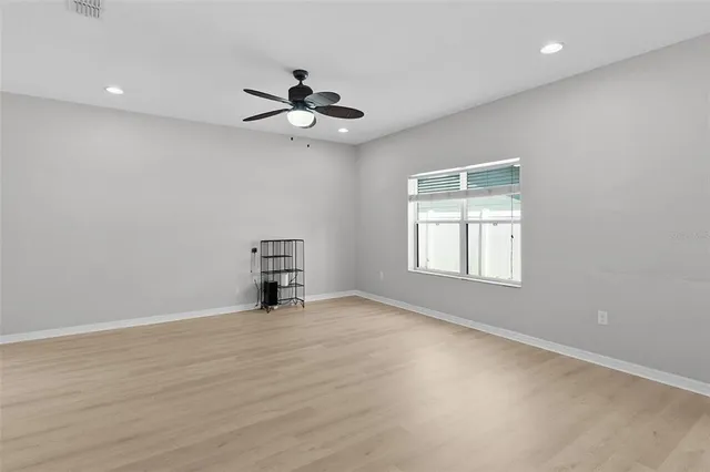 an empty room with windows and ceiling fan
