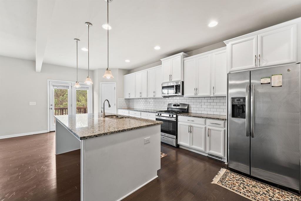 2415 Matlin Way Buford, GA 30519 - Photo 16 of 66 a kitchen with stainless steel appliances granite countertop a sink a stove a refrigerator and island with wooden floor